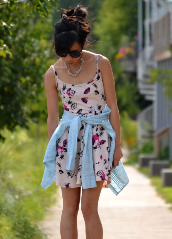 floral butterfly dress blue paisley button down shirt tied at the waist statement necklace heels hair bun top knot round sunglasses